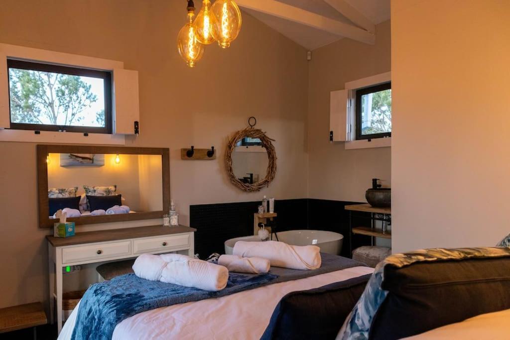 1 dormitorio con 2 camas, espejo y bañera en The Surfers Bush Cabin en Jeffreys Bay