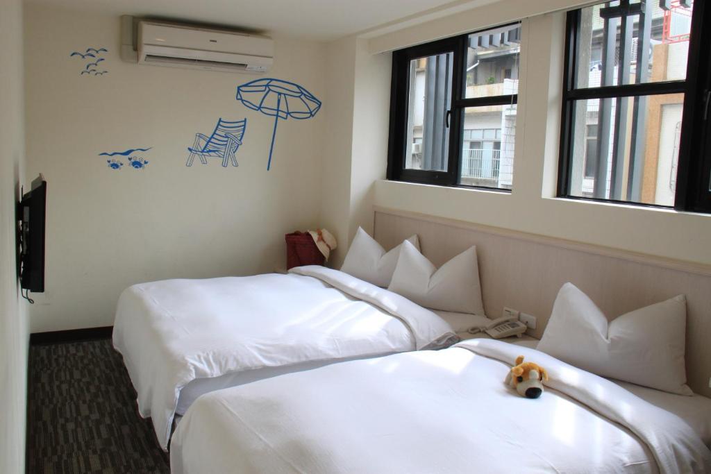 two beds in a hotel room with a teddy bear between them at Century Hotel in Kaohsiung