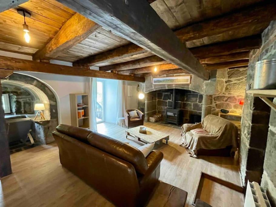 ein Wohnzimmer mit einem Sofa und einem Steinkamin in der Unterkunft Gîte du Pays-de-Salers, Cantal, classé 1* in Saint-Projet-de-Salers