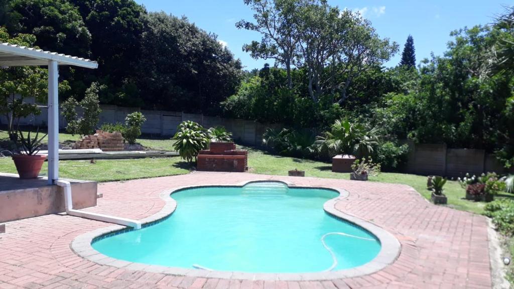 a swimming pool in a yard with a brick patio at HomeAway Beach House in Port Edward