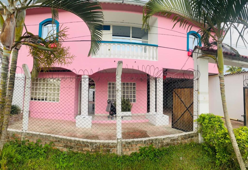 uma casa cor-de-rosa com uma vedação à frente. em Finca hotel casa rosada em Tuluá