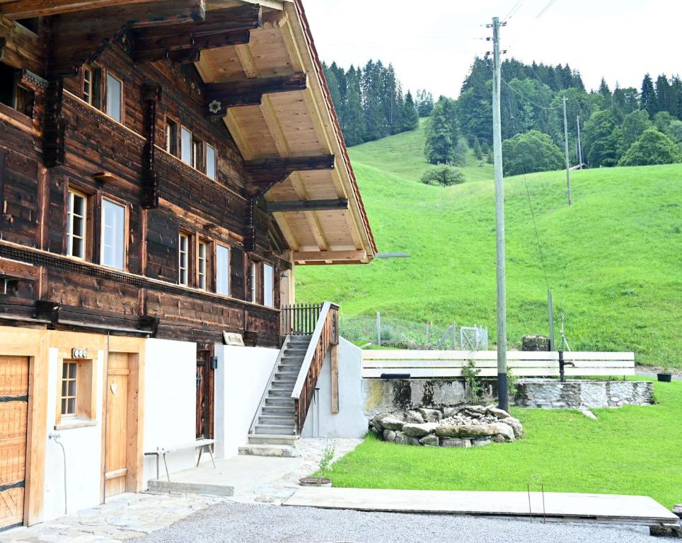 a wooden building with a staircase next to a green hill at Chalet Grittelihus, large bathroom, Lots of living space, nahe Interlaken in Diemtigen