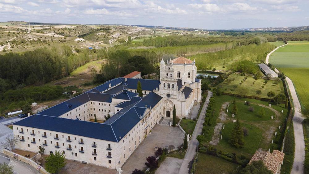 une vue aérienne sur un grand bâtiment avec un toit bleu dans l'établissement Hospedería Monasterio de La Vid, à La Vid y Barrios