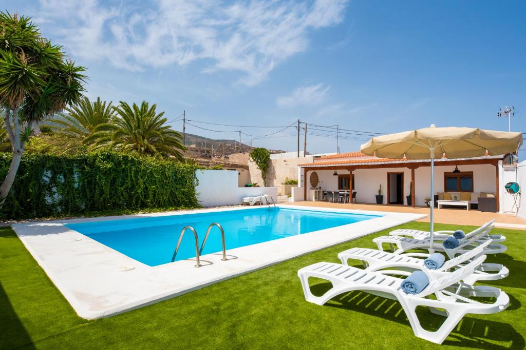 a swimming pool with lounge chairs and a house at Private house with pool & garden in Güimar