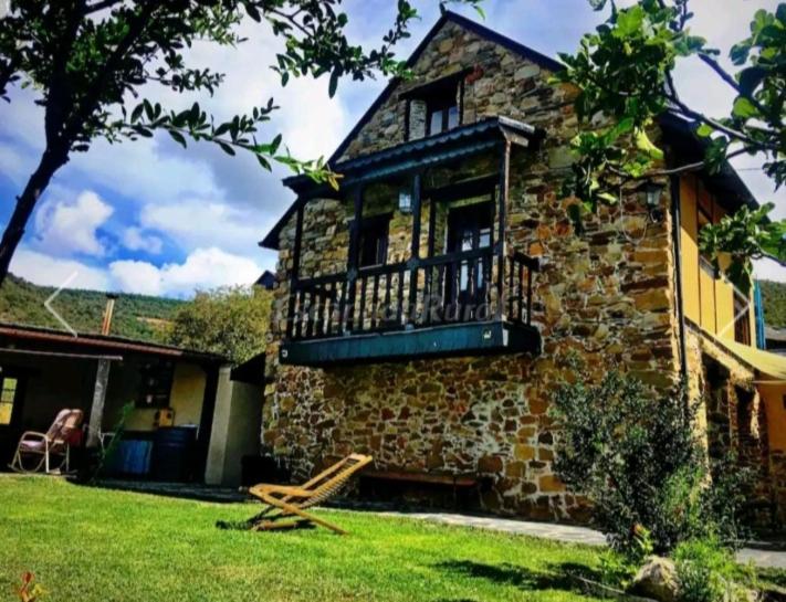 uma casa de pedra com uma varanda ao lado em Casa do Duende em Tejedo