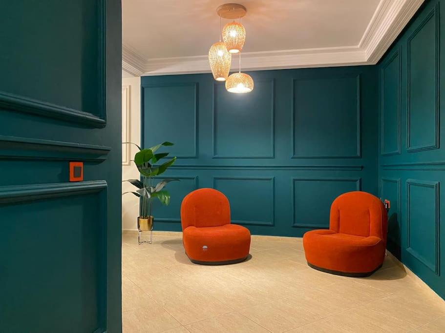 - deux chaises orange dans une chambre aux murs bleus dans l'établissement Appartement au cœur de Rabat, à Rabat