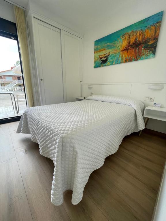 1 dormitorio con 1 cama blanca con manta blanca en Hostal montevideo, en Nigrán