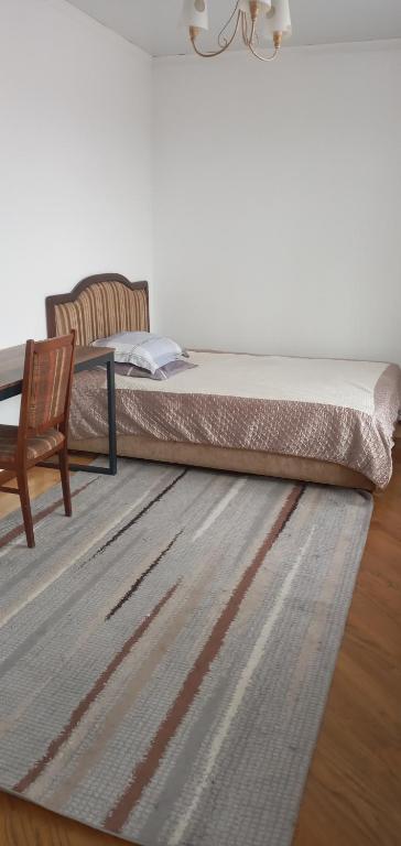 a bedroom with a bed and a chair and a rug at Уютная вилла в центре Бишкека in Bishkek