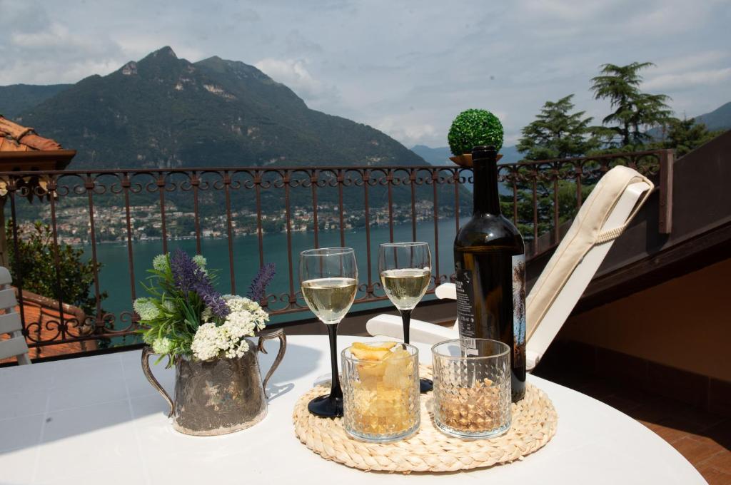 una mesa con una botella de vino y copas en el balcón en Appartamento "Bella vista" sul Lago di Como, en Faggeto Lario 