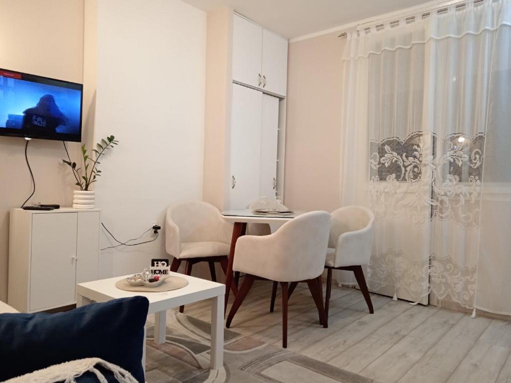 a white living room with a table and chairs at Red Square Apartment in Pirot