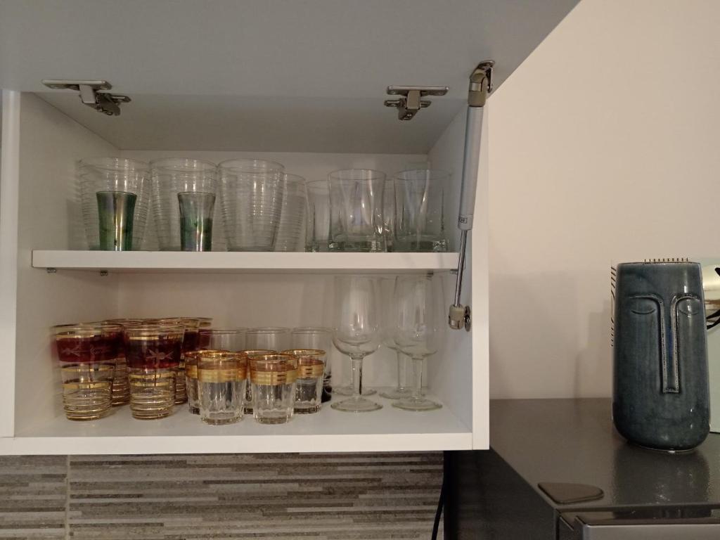 a cupboard filled with glasses and wine glasses at Red Square Apartment in Pirot