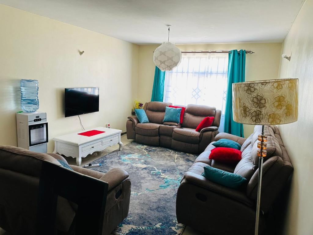 Sala de estar con 2 sofás y TV en Jacky's Milimani suites en Nakuru