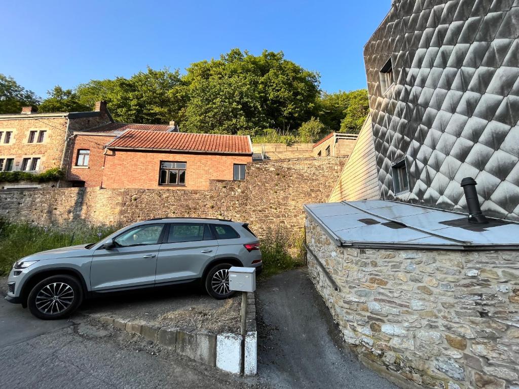 a silver car parked next to a stone wall at Charmante petite maison à Olne in Olne