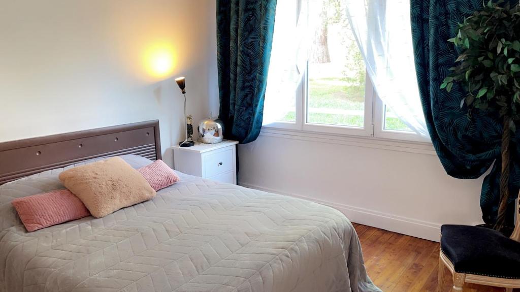 a bedroom with a bed with two pillows and a window at La chambre de Lou in Chatou