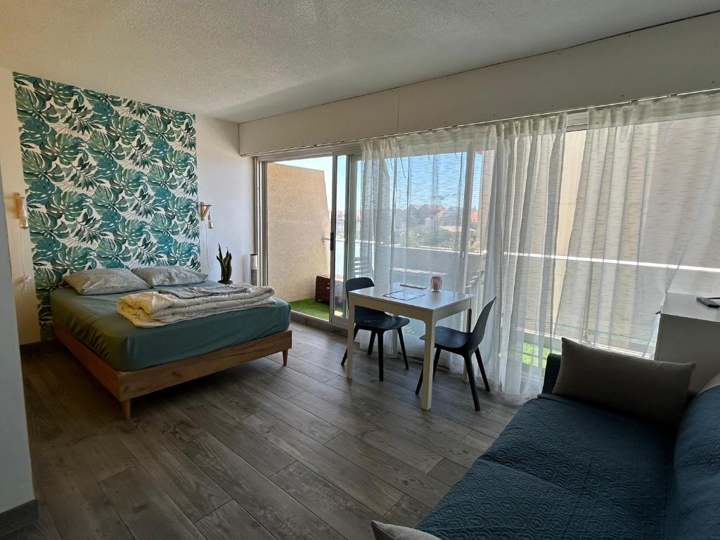 a bedroom with a bed and a desk and a table at Studio 2 pers avec vue sur l'océan in Lacanau