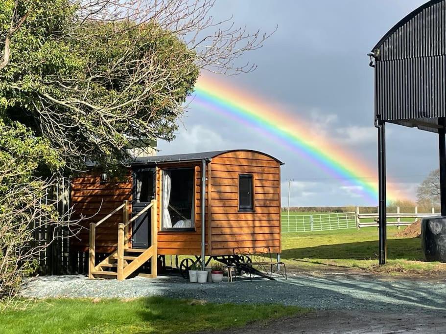 a wooden cabin with a rainbow in the background at Cosy Shepherd's Hut near Shrewsbury 