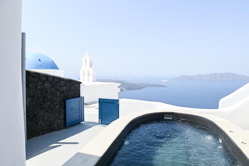 a plunge pool on the side of a house with the ocean in the background at Three Bells Suites in Firostefani