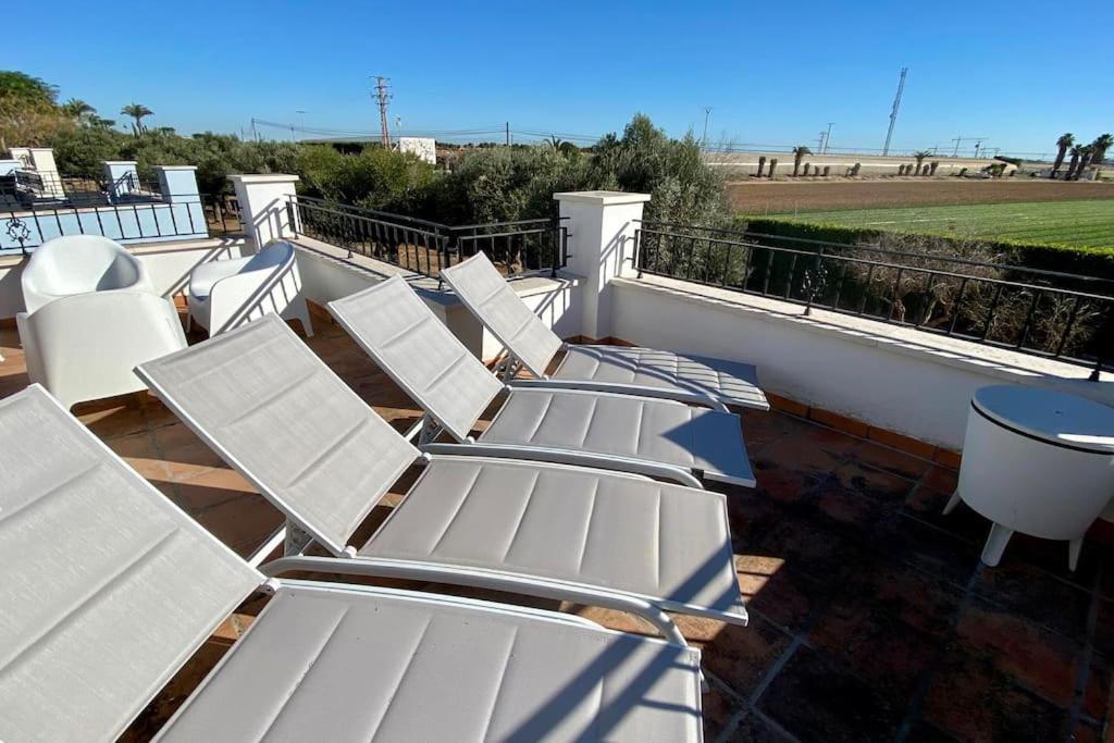 a row of white chairs sitting on a balcony at Villa Alegre - 2 bed villa with private heated pool on Mar Menor Golf - family friendly in Torre-Pacheco