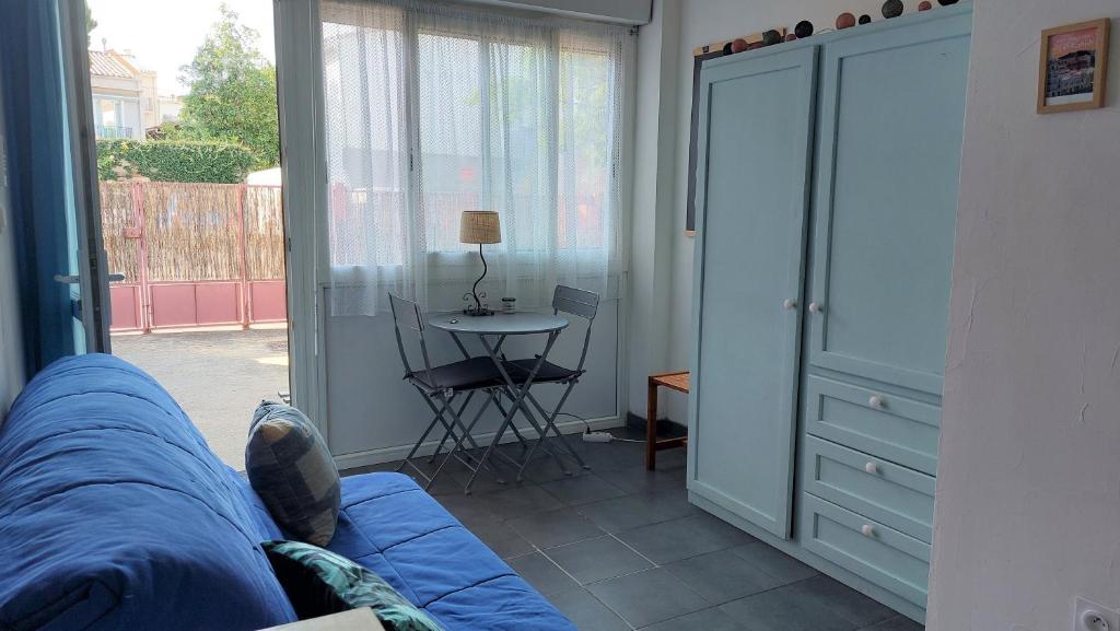 un salon avec un canapé bleu et une table dans l'établissement Chez Leslie et Vincent : logements climatisés avec parking privatif, à Perpignan