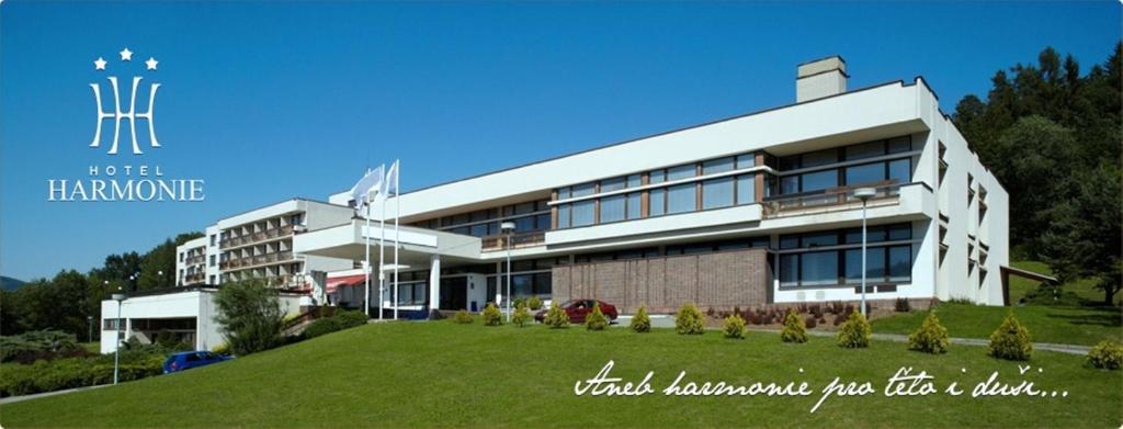 a building with a green lawn in front of it at Hotel Harmonie in Luhačovice