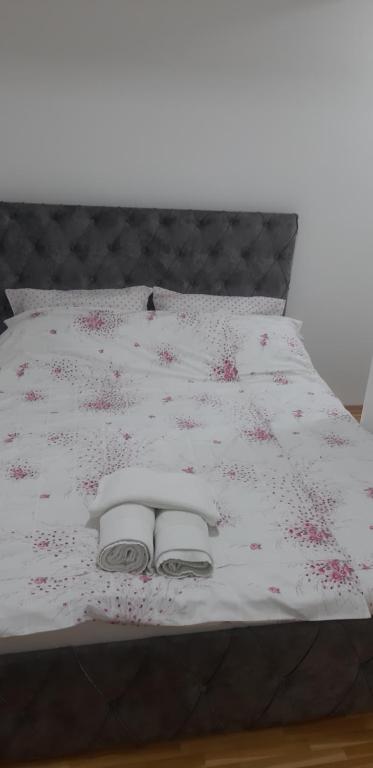 Una cama con sábanas blancas y flores rosas. en Mia DM Apartment, en Skopje