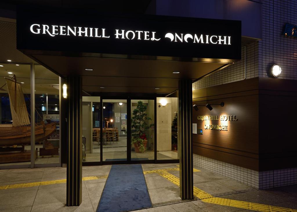 een gebouw met een bord voor een groen hotel bij Green Hill Hotel Onomichi in Onomichi