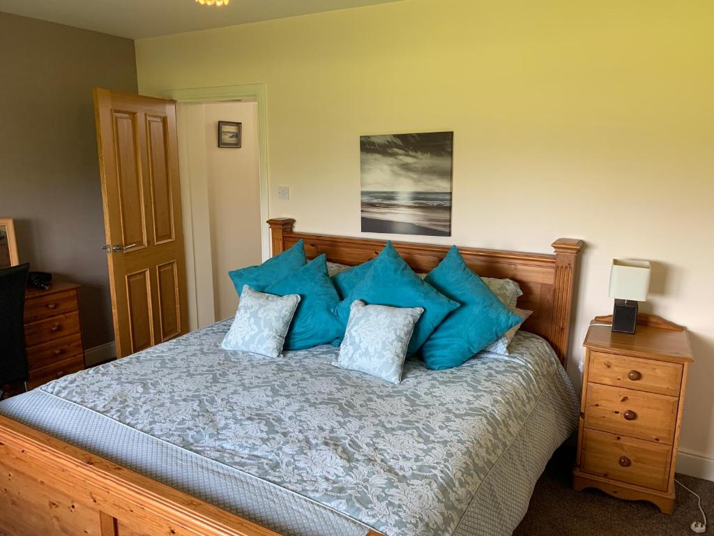 a bedroom with a bed with blue pillows at Glasphein Annex Inverness in Culloden