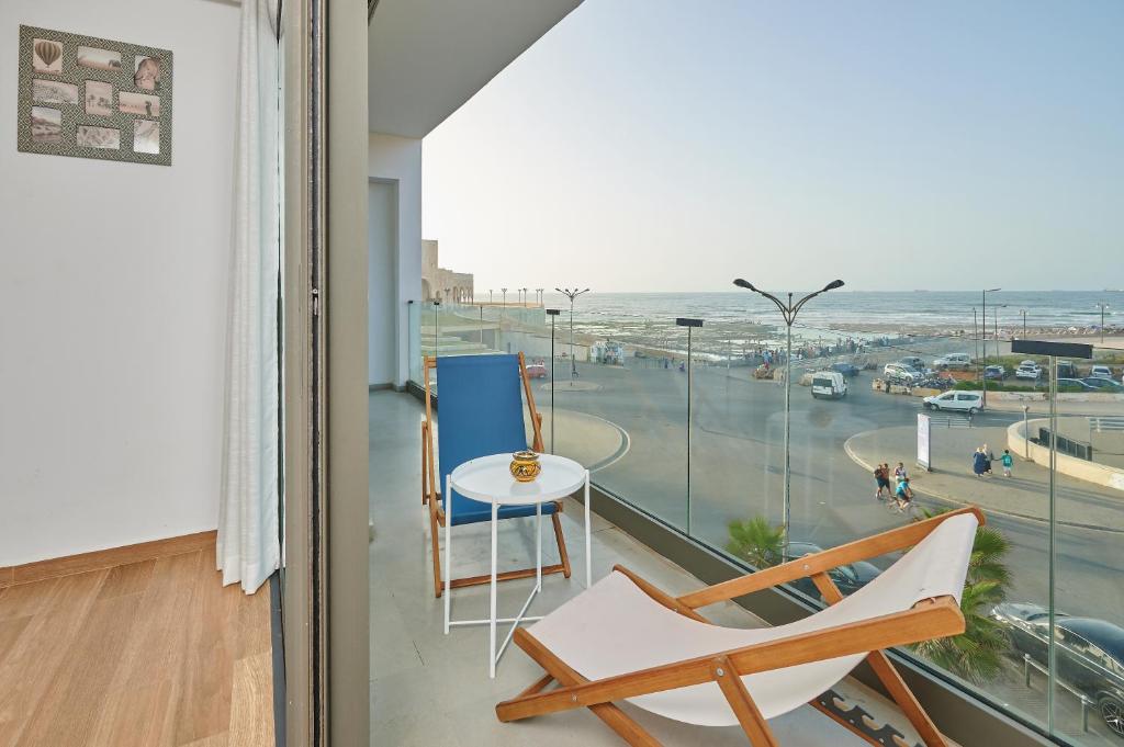 a room with a large window with a chair and a table at Apartment Sea View B7 - Mosquée Hassan II - By TheCasaEdition in Casablanca