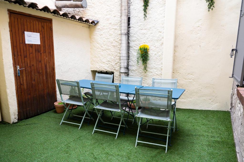 una mesa azul y sillas sentadas en la hierba en Hôtel-restaurant le Palais, en Apt