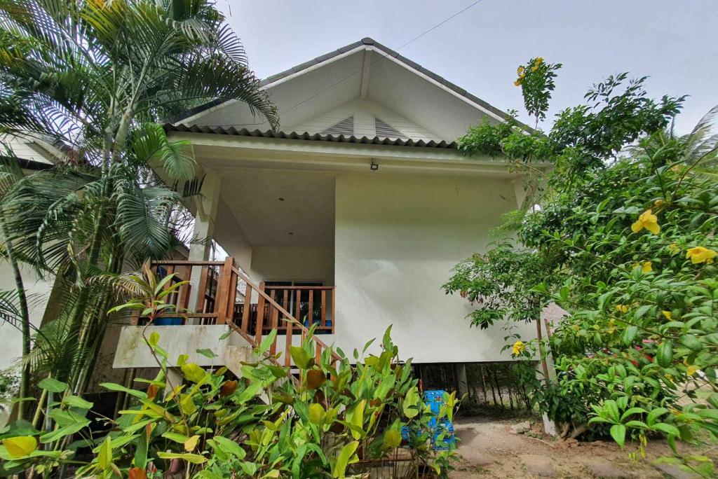 a white house with a balcony and trees at Niniari House in Thong Sala