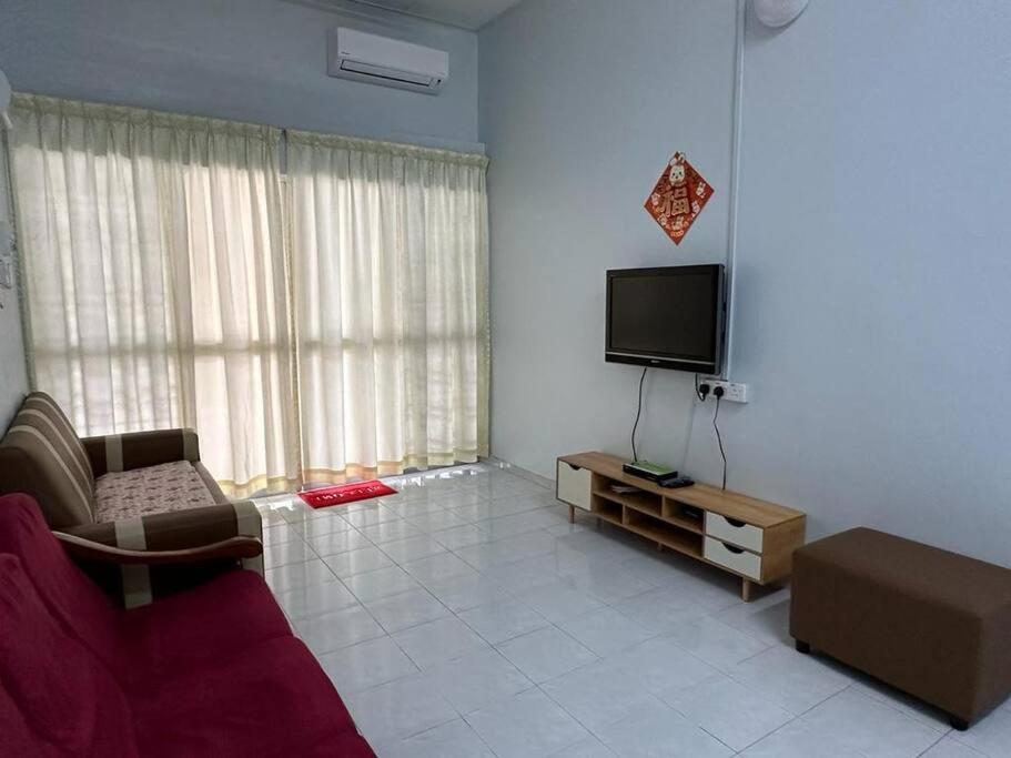 a living room with a couch and a flat screen tv at Guan Homestay Sungai Besar 大港民宿 in Sungai Besar