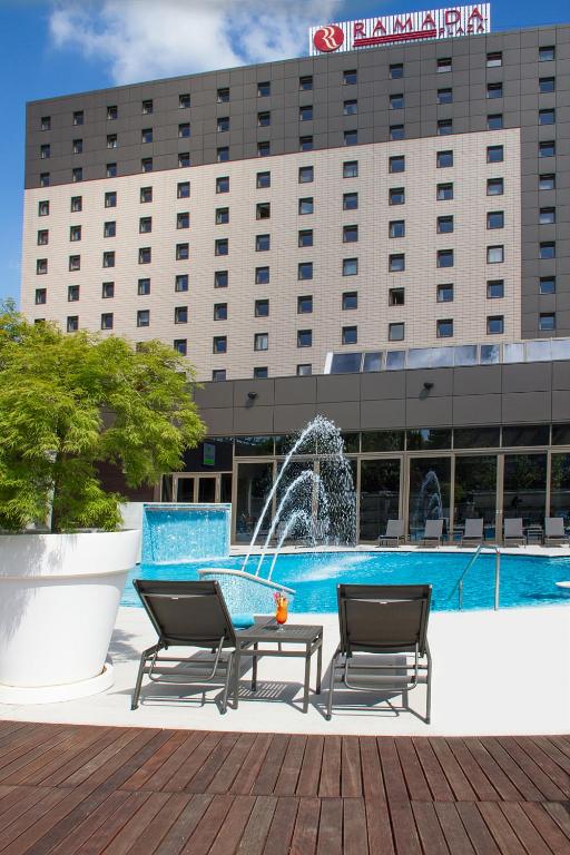 a fountain in front of a building with two chairs and a table at Ramada Plaza by Wyndham Bucharest Convention Center in Bucharest