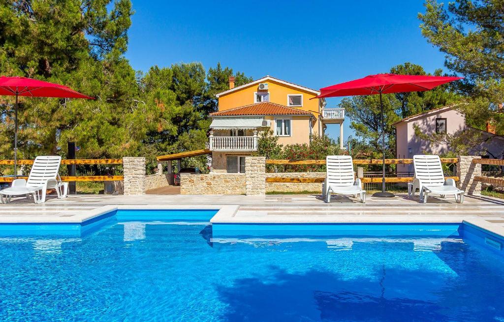 een zwembad met stoelen en parasols voor een huis bij Ferienwohnung mit großem Pool nur 500 Meter bis zum Kieselstrand mit Klima, WLAN, Terrasse, Grillplatz in Ližnjan