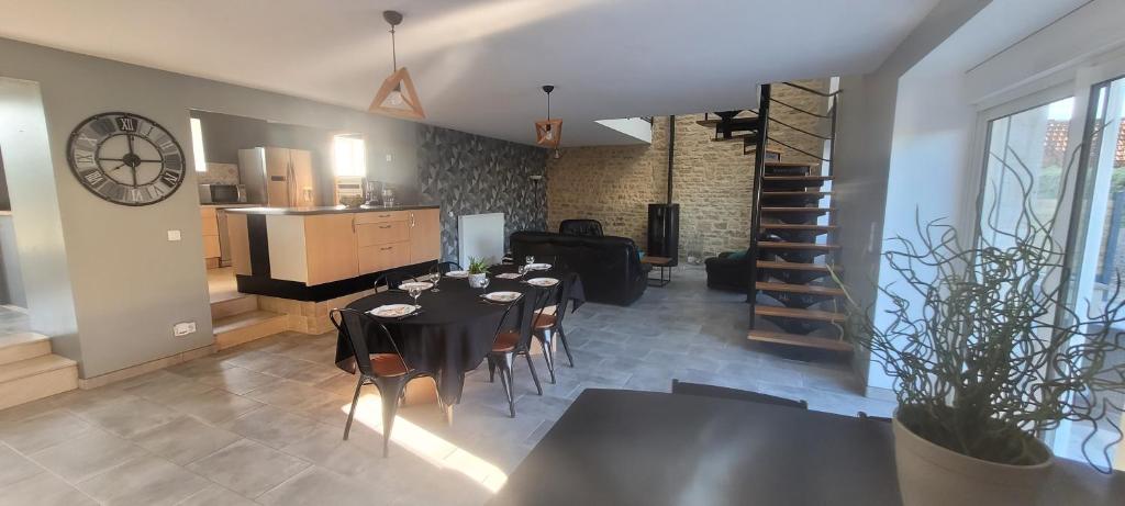 a dining room with a table and chairs and a clock at Belle maison en pierre avec cour in Huberville