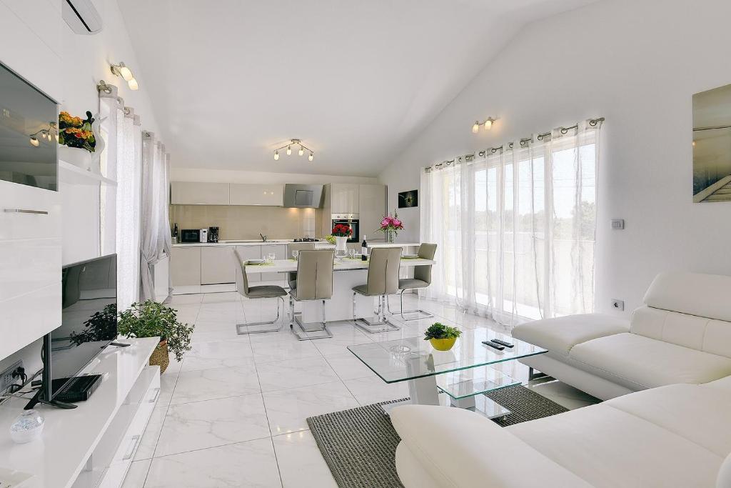 a living room with white furniture and a kitchen at Appartement mit großem Garten und Grillbereich in Valtura