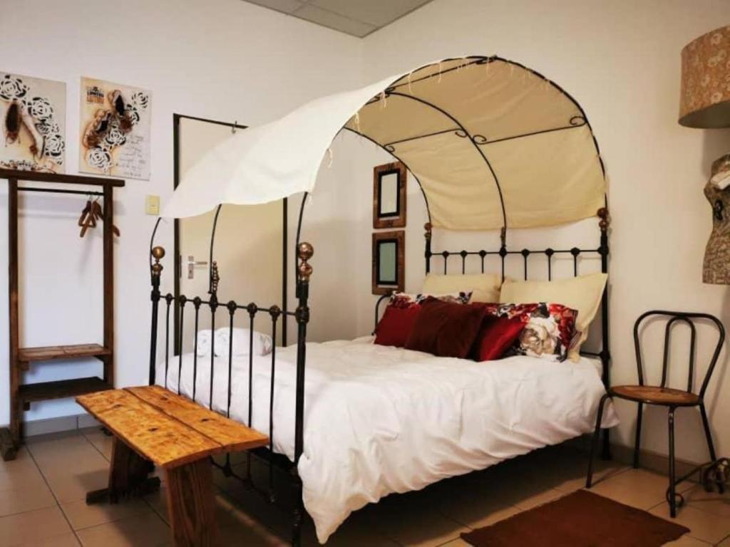 a bedroom with a canopy bed and a wooden table at Leather and Lace & a Suitcase in Groutfontein