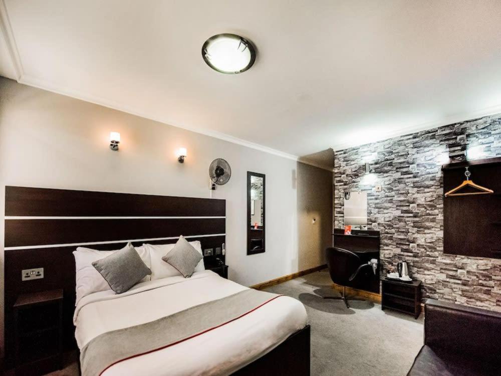Pokój hotelowy z dużym łóżkiem i biurkiem w obiekcie Epsilon Hotel w Londynie