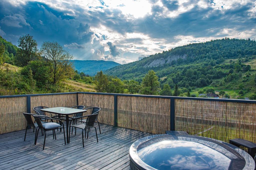 une terrasse avec une table et des chaises ainsi qu'un bain à remous dans l'établissement K2 House, à Skole