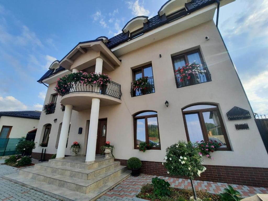 una gran casa blanca con flores en las ventanas en AristoCat Hotels Rasnov, en Râșnov