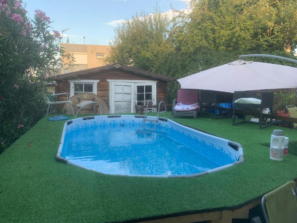 a small swimming pool on grass with an umbrella at Chambre tout confort Saphir 1 à 3 P dans belle maison in Vaulx-en-Velin