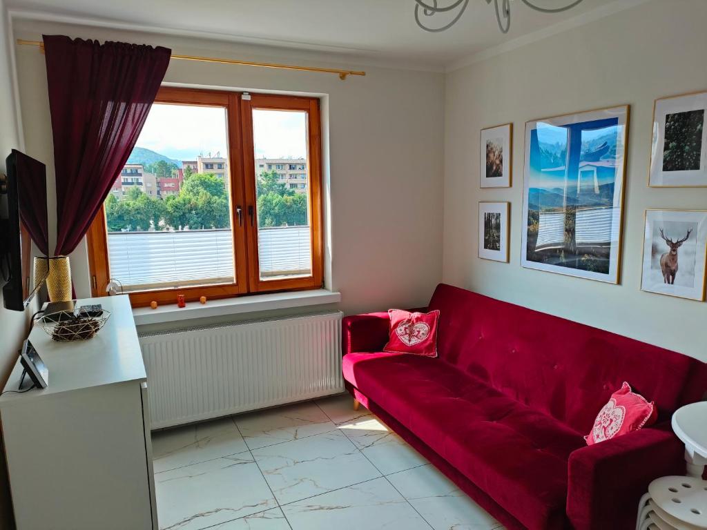sala de estar con sofá rojo y ventana en Apartament Centrum, en Ustroń