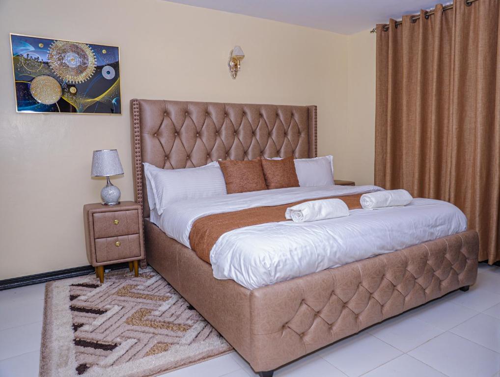 - une chambre avec un grand lit et une tête de lit marron dans l'établissement Milimani Apartment Comfy Homestay, à Nakuru
