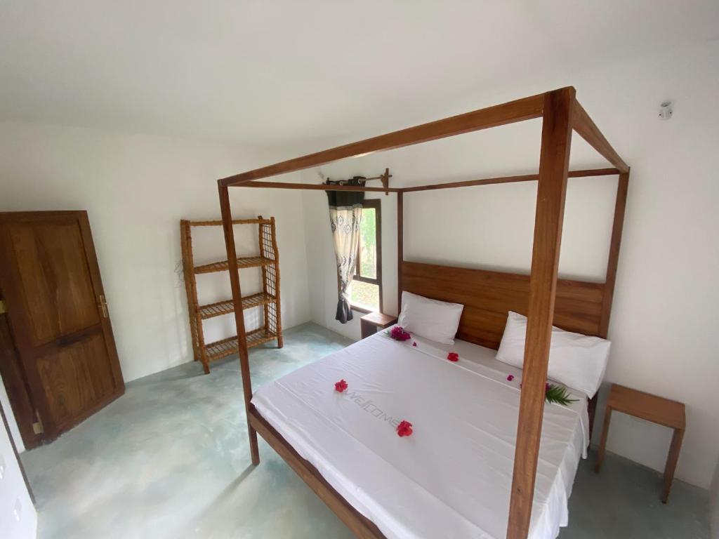 a bedroom with a canopy bed with red flowers on it at Blue Villa Zanzibar in Pwani Mchangani