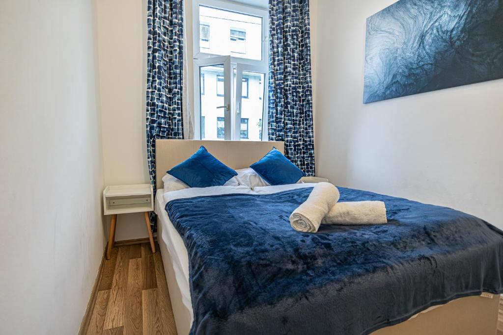 um quarto com uma cama com lençóis azuis e almofadas azuis em Modern Comforts: Chic Studio Apt Centrally Located em Viena