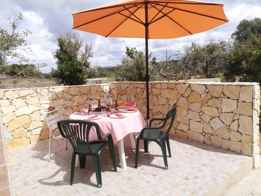 een tafel met een parasol op een patio bij Casa Manuel J. J. M -Alfambras, Aljezur - Quiet Country House in Aljezur
