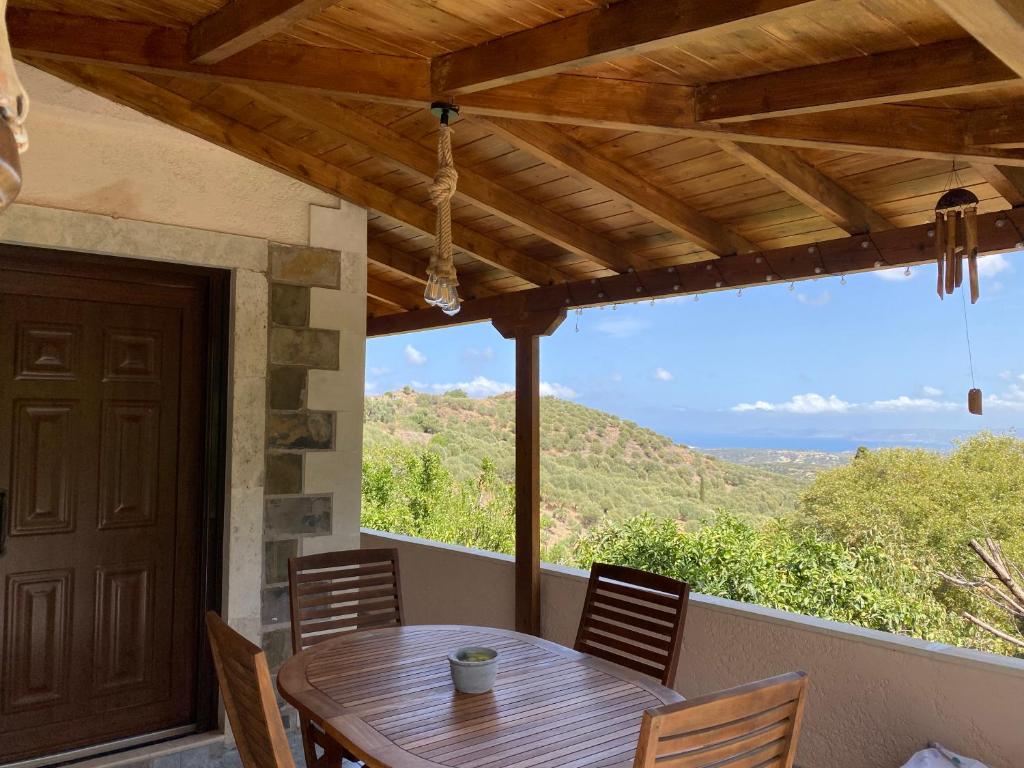 une table et des chaises en bois sur un porche avec vue dans l'établissement The Garden House, Sitia, à Siteía