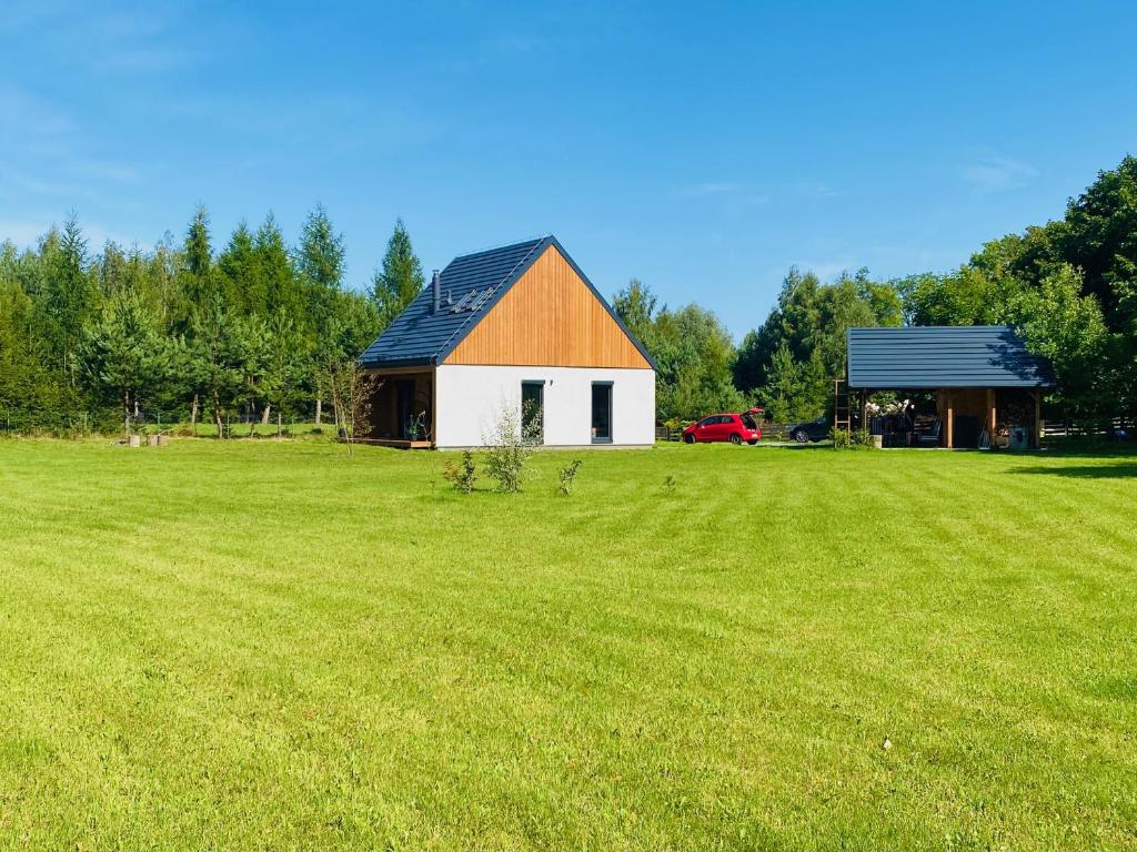 a barn in a field with a large grass field at Rajska nowoczesna stodoła !!! in Dźwierzuty