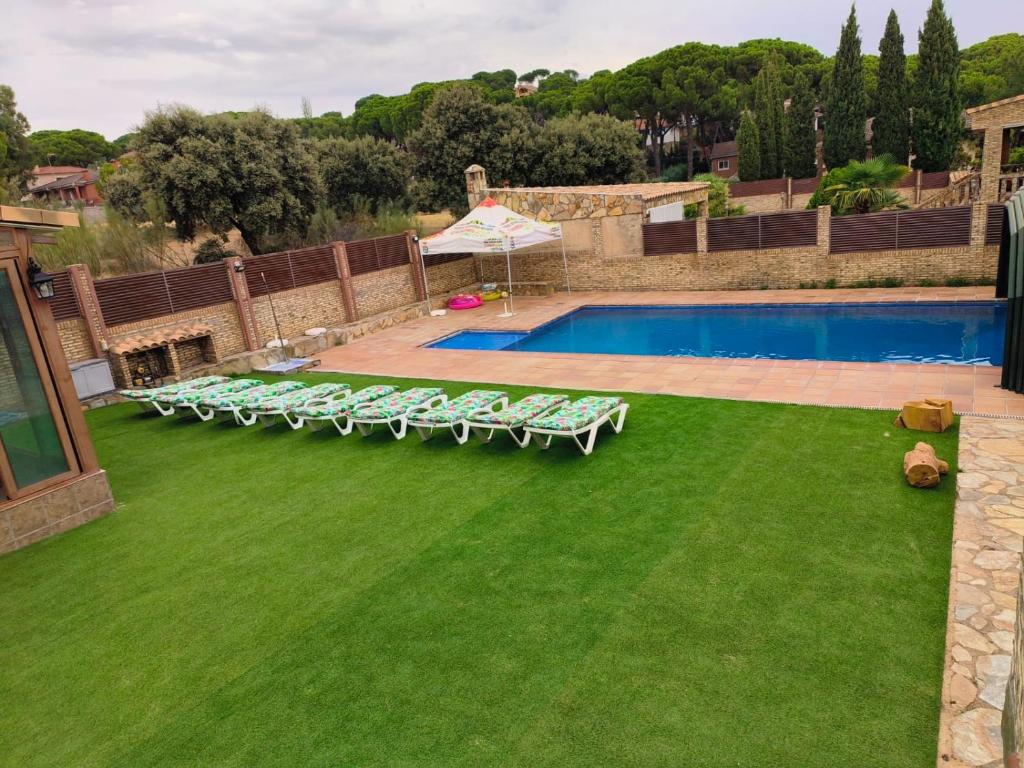 eine Gruppe von Liegestühlen und einem Pool in der Unterkunft Casa Grande Del Pinar in Almorox