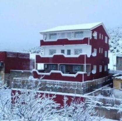 un gran edificio rojo con nieve. en The Zawi Legacy, en Imouzzer Kandar