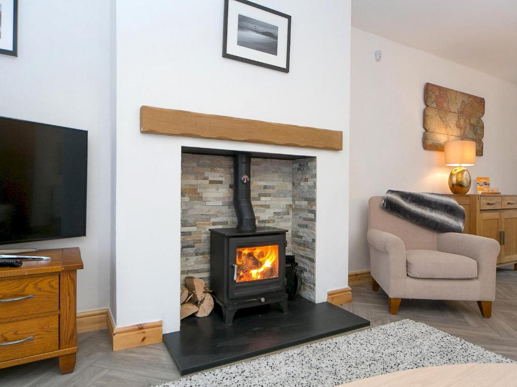 ein Wohnzimmer mit einem Kamin und einem TV in der Unterkunft Pass the Keys Modern Coastal Home in Bull Bay in Amlwch